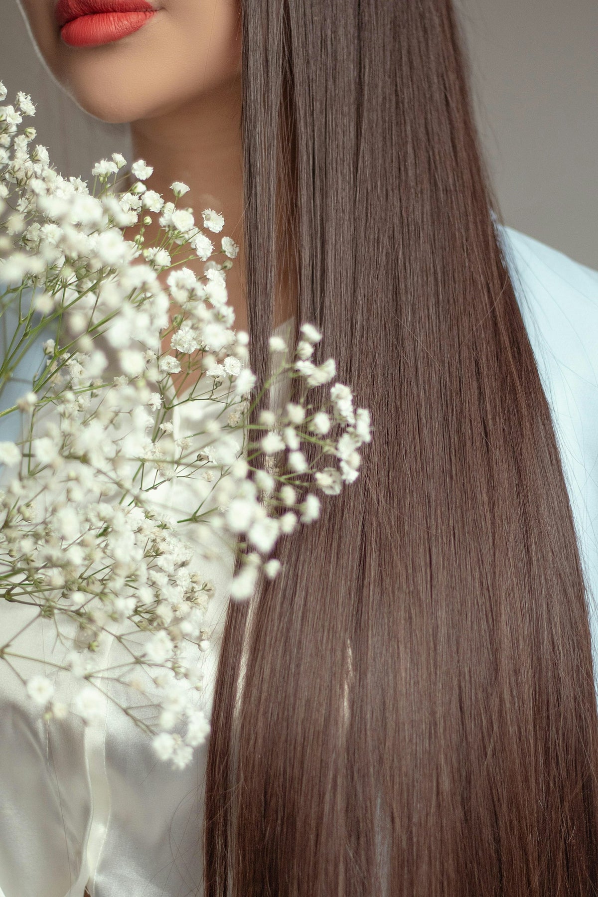 Femme aux longs cheveux bruns tenant des fleurs blanches